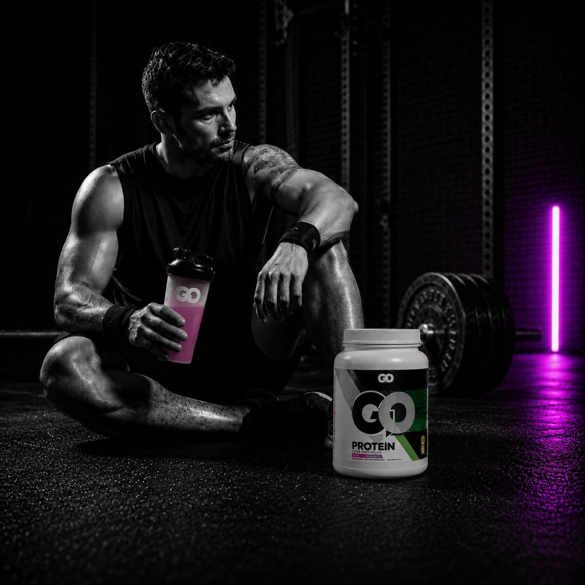 Athlete resting in the gym with a GO Protein shaker and tub after a workout